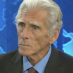 Steve Cohen - Older man with silver hair in a suit and red tie speaking in a TV studio with a blue backdrop.